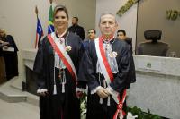 Duas pessoas posando para foto dentro de um Plenário, sendo uma mulher e um homem. Ambos vestidos com a toga.