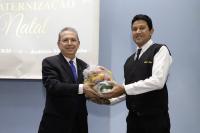 Dois homens posando para foto, onde o da esquerda entrega a cesta básica de alimentação para o da direita.