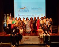 Grupo de pessoas posando para foto dentro de um auditório. Ao fundo, tela projetada com texto escrito ZENABIJUD, ENCONTRO NACIONAL DE BIBLIOTECAS DO PODER JUDICIÁRIO.