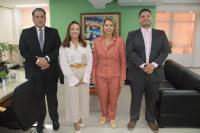 Quatro pessoas, duas mulheres ao centro e dois homens, posando para foto dentro de uma sala.