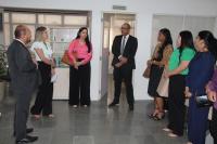 Foto de sete pessoas posicionadas em pé, formando um semi-círculo. As pessoas estão conversando dentro de uma sala. 