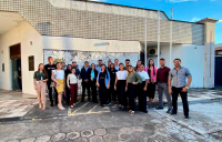 Grupo de pessoas posando para foto em frente à uma fachada da vara trabalhista.