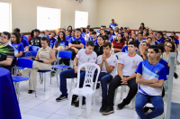 Foto mostra jovens alunos sentados em um grande auditório, sendo capacitados pelo projeto Caminhos da Liberdade.