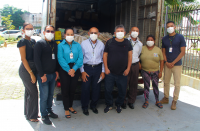 Foto de servidores posicionados diante de um caminhão carregado de processos antigos descartados para reciclagem