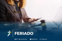 Foto parcial de uma mulher de cabelos claros, usando blazer marrom, segurando um celular na mão esquerda e um martelo de juiz na mão direita, em frente a um notebook aberto. Ao seu lado, vê-se uma balança, representando a Justiça. Em primeiro plano, uma tarja azul com o texto branco FERIADO ao lado da logomarca do TRT-16. Abaixo do texto, os ícones e endereços do TRT-16 nas redes sociais.