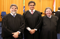 Foto de três homens claros, sorrindo e usando togas pretas de juiz. Atrás deles, parede amadeirada.