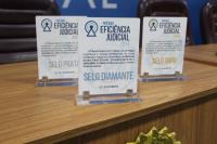 Foto mostra no primeiro plano placa de acrílico em homenagem aos agraciados com o Prêmio Eficiência Judicial.