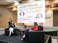 Foto mostra duas melheres sentadas em poltronas. Ao fundo um painel destaca a informação 2ª Semana do Trabalho Decente