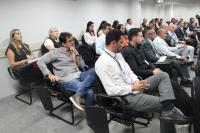 Foto mostra várias pessoas sentadas em cadeiras de um auditório.