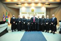 Nove pessoas, entre homens e mulheres estão perfilados e usando togas. Ao fundo em uma parede clara o nome TRIBUNAL REGIONAL DO TRABALHO - 16ª Região
