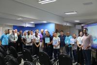 Foto de pessoas em pé, dentro de um auditório.