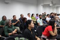 A foto mostra homens e mulheres sentados em cadeiras dentro de um auditório. São servidoras, servidores, terceirizadas e terceirizados do TRT-16