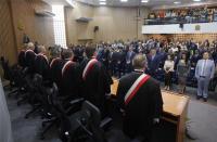 Foto panorâmica de auditório lotado com pessoas de pé no palco, na plateia e no mesanino. 