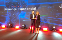 Foto mostra um homem e uma mulher em um palco. Ao fundo um painel informando: Categoria Exponencial