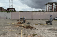Foto mostra homens trabalhando em um pátio do estacionamento de veículos