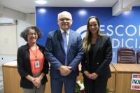 Foto mostra duas mulheres e um homem. Ambos estão, um ao lado do outro e em pé, dentro do auditório da EJud-16