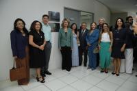 Foto mostra um grupo de pessoas em pé ao lado de uma placa inaugural