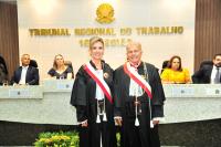 Foto mostra uma mulher e um homem, em pé, ambos estão usando togas. Ao fundo o nome do Tribunal Regional do Trabalho da 16ª Região