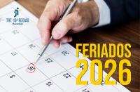 Arte feita com imagem de um calendário e uma mão de uma homem segura uma caneta marcando uma data. No canto inferior direito a informação: FERIADOS 2026
