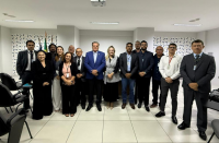 Foto mostra um grupo de pessoas, todos reunidos em um auditório