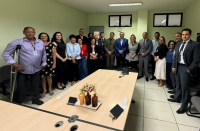 Foto mostra um grupo de pessoas, entre homens e mulheres todos em pé em uma sala de audiência