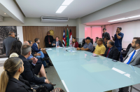 Foto mostra pessoas sentadas em volta de uma mesa de reunião