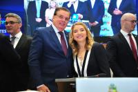 Foto de um homem ao lado de uma mulher no primeiro plano. 