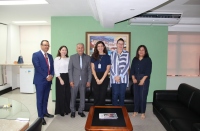 Foto mostra seis pessoas em pé. Uma ao lado da outra. Elas estão em uma sala de gabinete.