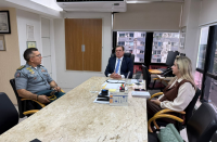 Foto mostra 2 homens e uma mulher. Ambos estão sentandos ao redor de uma mesa.