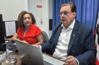 Foto mostra uma mulher e um homem, ambos estão sentados.
