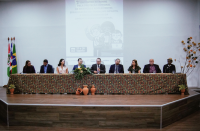 Foto de mesa de honra em evento com nove pessoas.