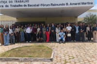 Foto mostra várioas pessoas em pé, na frente de um prédio. Na marquise o nome: Justiça do Trabalho Vara do Trabalho de Bacabal