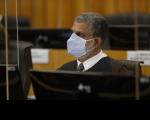 Foto do ministro Lelio Bentes Corrêa, do Tribunal Superior do Trabalho, sentado em sua bancada, em frente a um monitor, usando máscara branca, trajando toga escura, camisa branca e gravata listrada