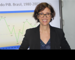 Foto da professora doutora da Unicamp Marilane Teixeira durante aula ministrada na 17ª Semana de Formação de Magistrados. Marilena tem cabelos castanhos claros curtos, está usando óculos e vestindo blazer preto sobre roupa estampada