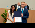 Foto da servidora Edvânia Kátia, do TRT do Maranhão recebendo do juiz Carlos Alexandre Bötcher a menção honrosa à Série Música pela Infância do I Prêmio da Memória do Poder Judiciário   