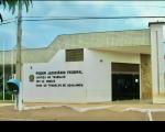 Imagem da fachada da sede da VT de Açailândia na cor branca, com porta de vidro em tom escuro, denominação da Vara Trabalhista, sendo possível visualizar o céu, um poste e um orelhão. 