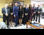 Imagem de conjunto do presidente do TRT-16 ao lado de magistradas e magistrados em pé tendo ao fundo uma parede amarela e quadro.