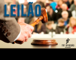 Em destaque mão masculina em movimento de batida de martelo de leiloeiro.