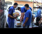 Foto de terceirizados do TRT-MA descarregando alimentos da carroceria de uma caminhonete branca no portão da Casa Acolher.