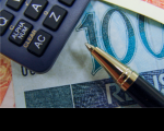 Foto mostrando partes de calculadora, caneta e nota de R$100.
