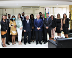 Foto do presidente do TRT, desembargador Carvalho Neto (vestindo blazer azul, calça preta e gravata azul), do juiz Saulo Fontes (usando paletó azul marinho e gravata listrada de cinza e branco), ladeados pelas servidoras e servidores empossados, no Gabinete da Presidência.