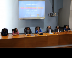 Foto de pessoas sentadas à mesa de honra no auditório onde foi realizado o evento