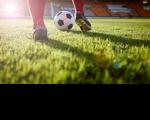Atleta de futebol conduzindo a bola em um campo de futebol