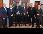 Seis autoridades do Judiciário Federal e Estadual que vestem ternos escuros e estão lado a lado sobre tapete e tendo ao fundo pintura com representação da deusa da Justiça