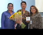 Foto de um homem e duas mulheres, uma delas segurando um buquê de flores.