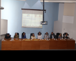 Foto de mulheres e homens sentados à mesa de honra do evento