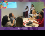 duas mulheres falam ao público de outras quatro mulheres sentadas à mesa 