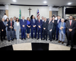 grupo de homens e mulheres em plenário. Ao fundo, crucifixo, bandeiras do Maranhão e do Brasil.