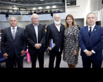 Foto de três desembargadores, uma desembargadora e palestrante. Todos estão lado a lado e em posicionados  no palco do auditório.