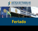 Fachada do prédio-sede do TRT16 com bandeiras hasteadas do Brasil, do Maranhão e do Tribunal. Abaixo, texto Feriado na cor amarela sobre faixa azul. 